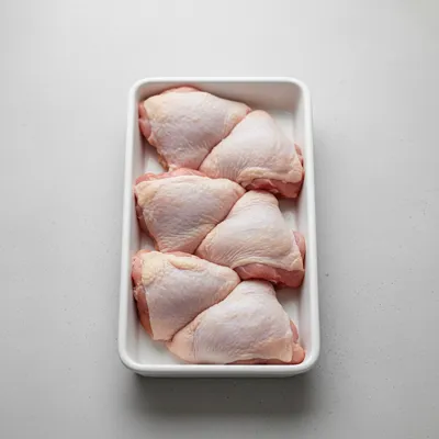Raw chicken thighs on a tray