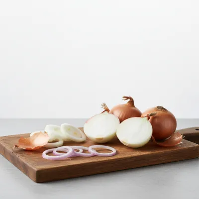 Whole and sliced onions on a cutting board